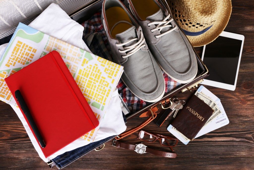 Packed suitcase of vacation items on wooden table