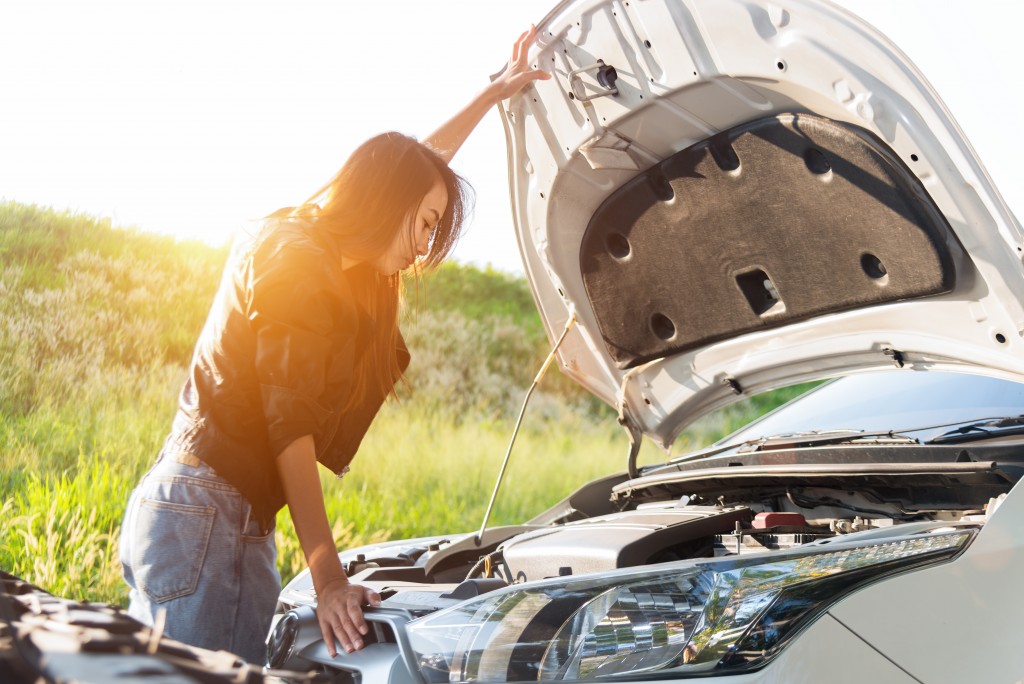 Woman inspecting car open hood
