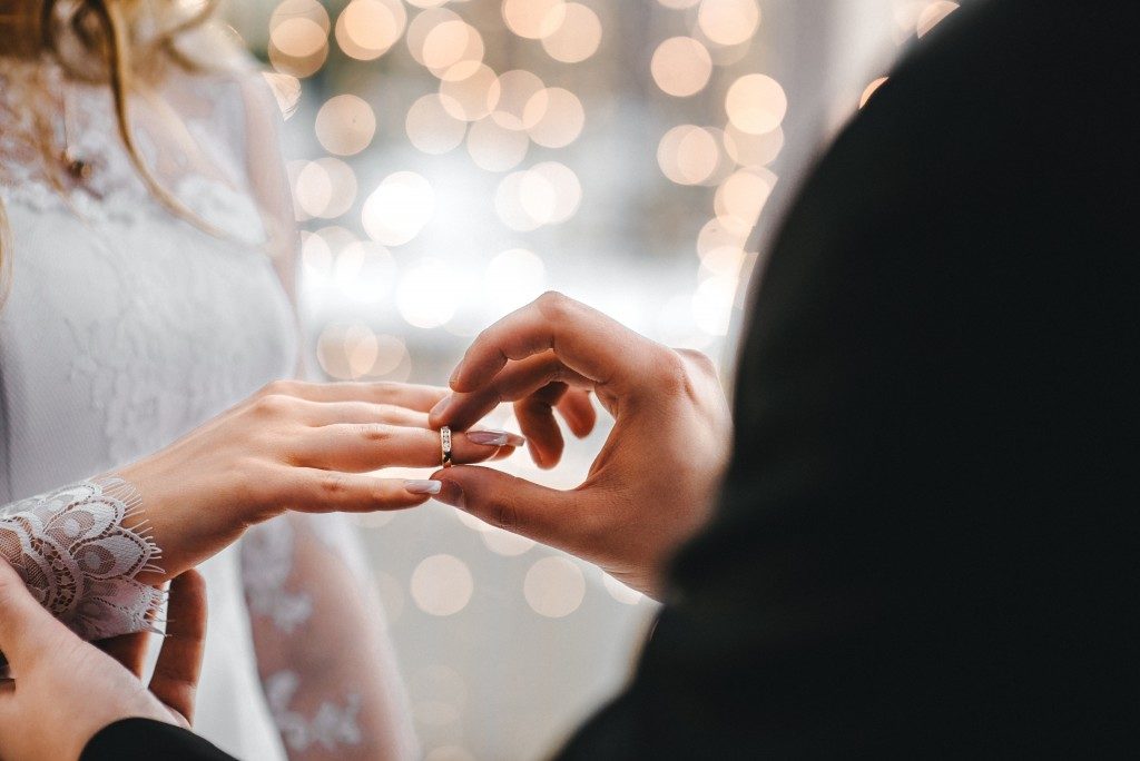 Groom placing ring on her bride's finger