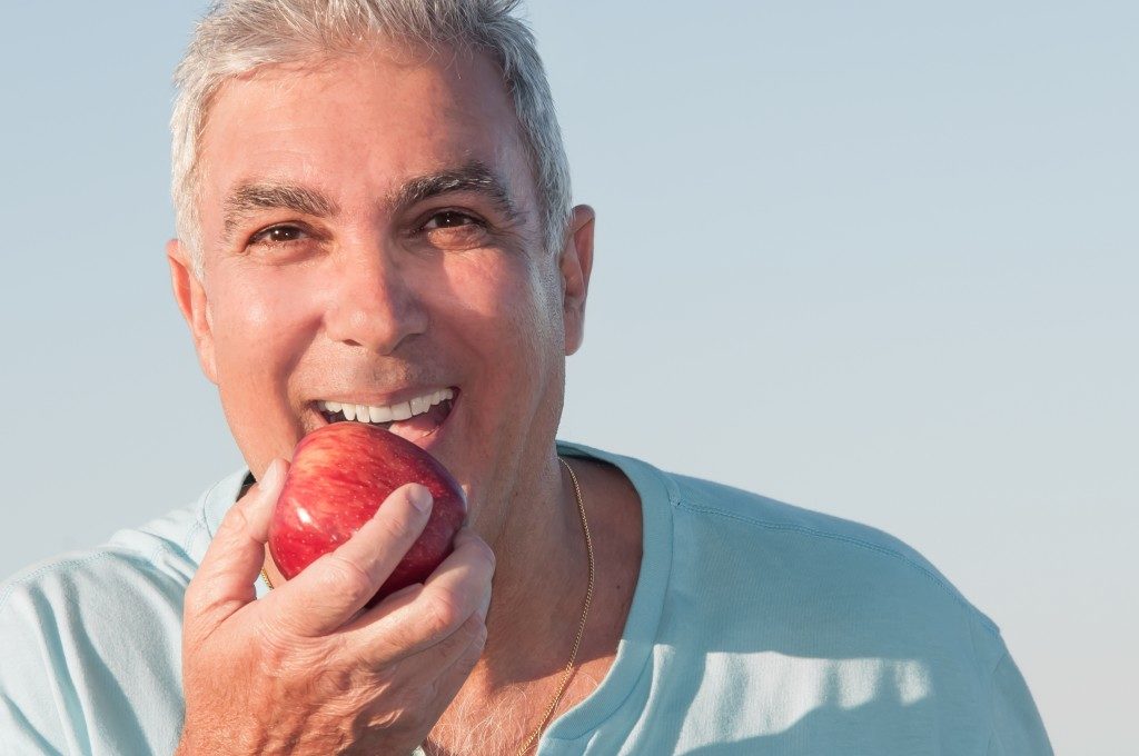man eating an apple outdoors