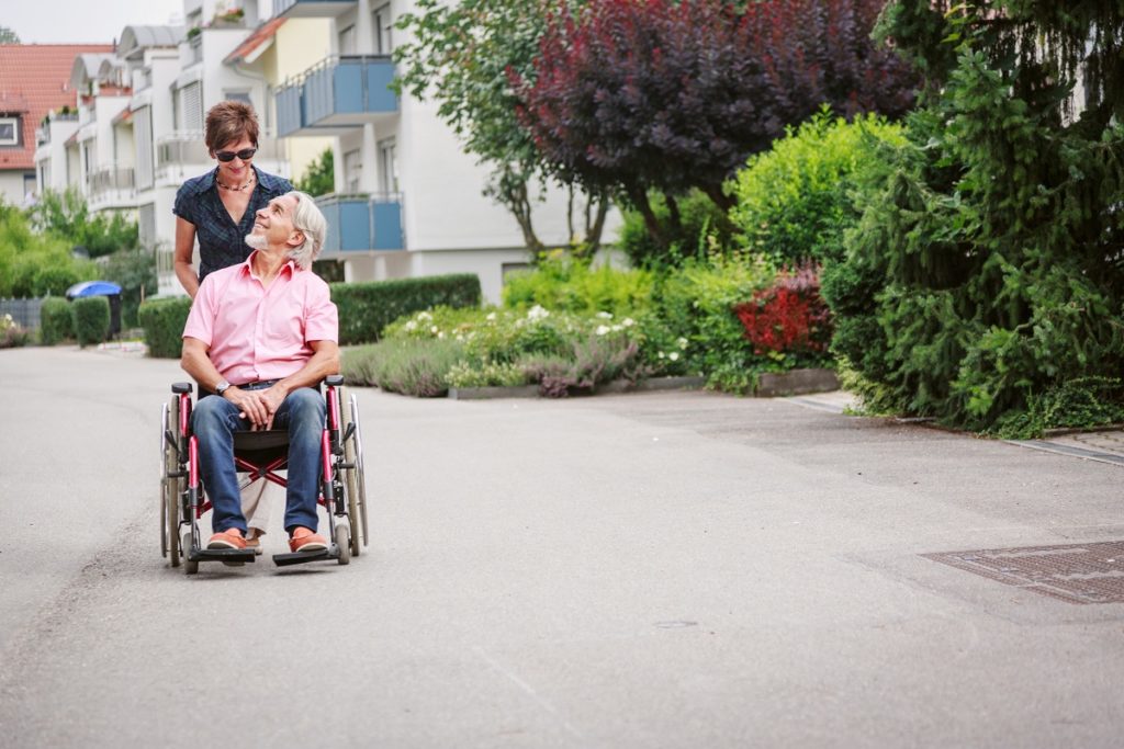 woman pushing wheelchair of old man