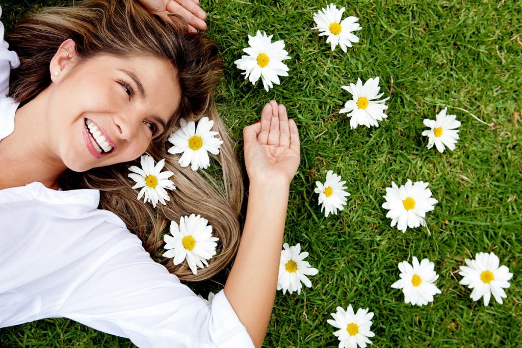 happy woman on the grass with scattered flowers