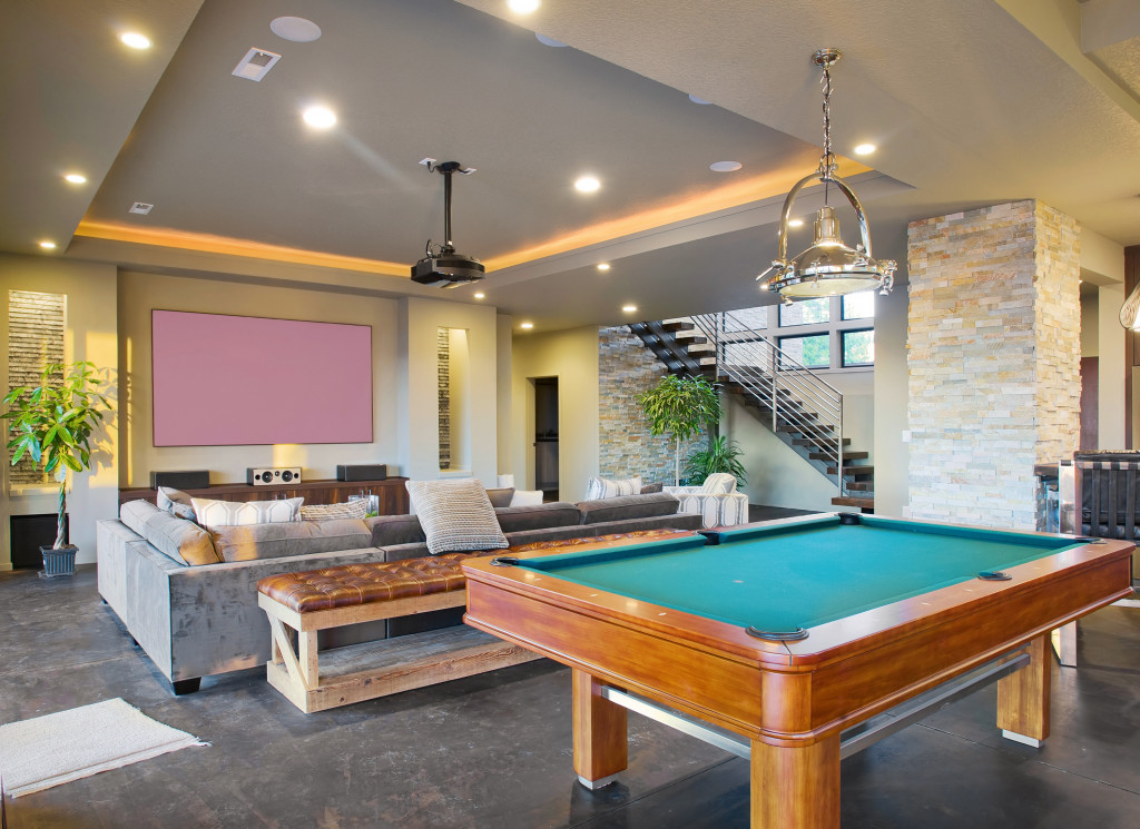 a billiard table, sofa, and a big television inside a house space