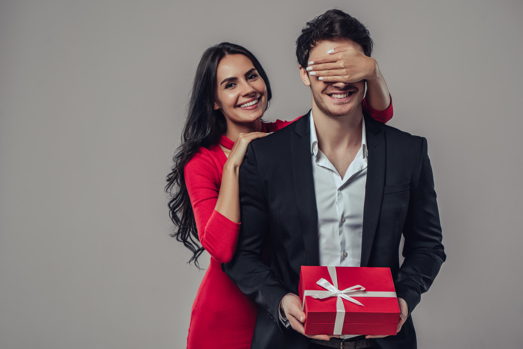 A woman giving her partner a surprise gift