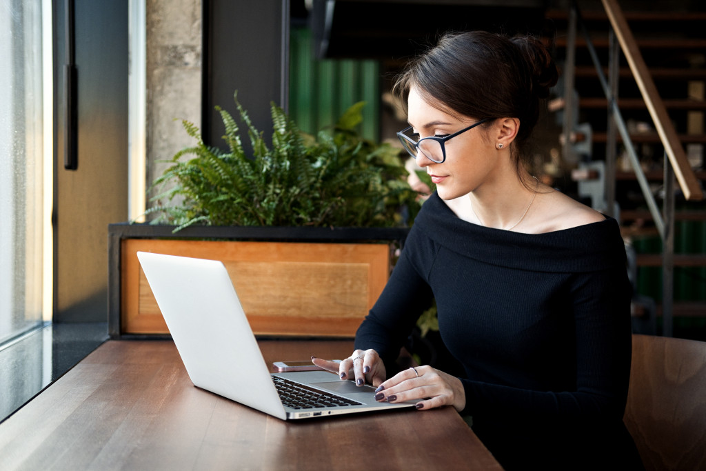 Young woman wearing glasses while working online in a coffee shop.