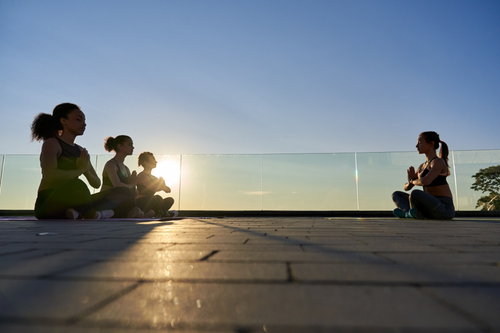 A group of women doing yoga outdoors during sunrise