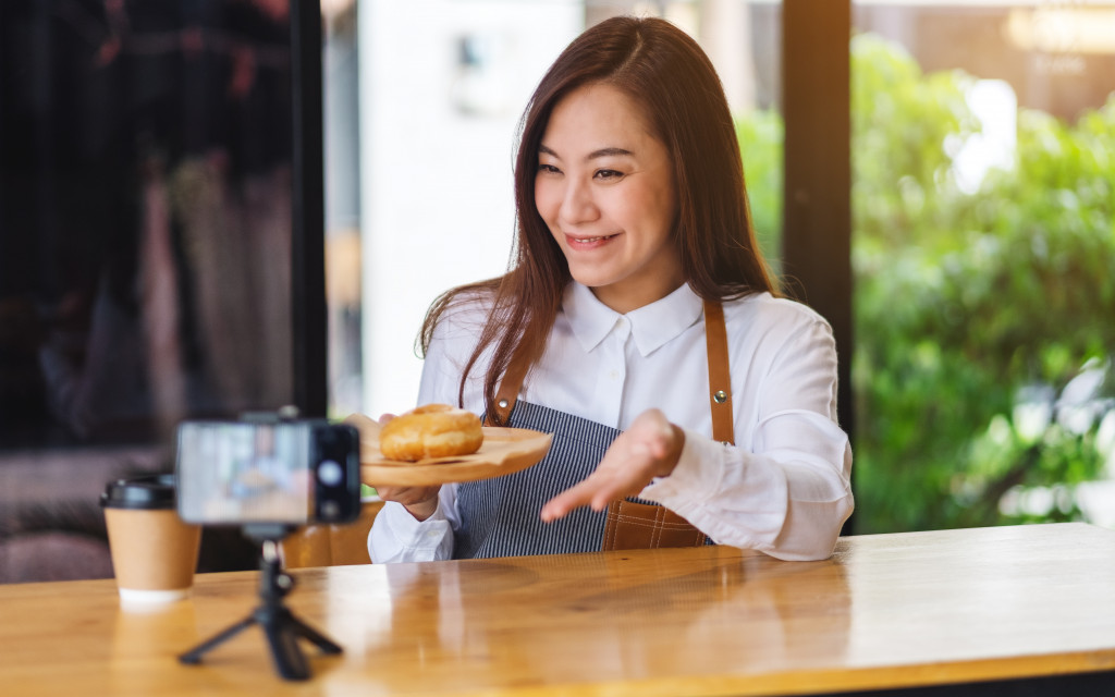 a young woman showing food on a phone camera in a tripod