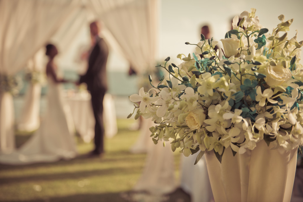 a near beach wedding venue with bride and groom blurred and flowers in vase in foreground