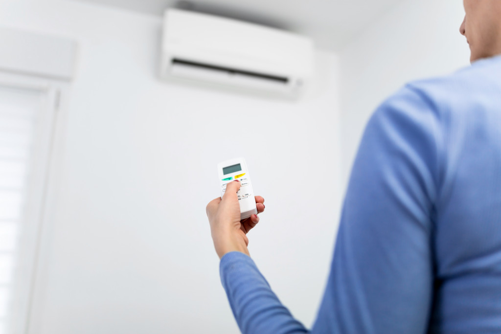 woman holding remote of aircon at home