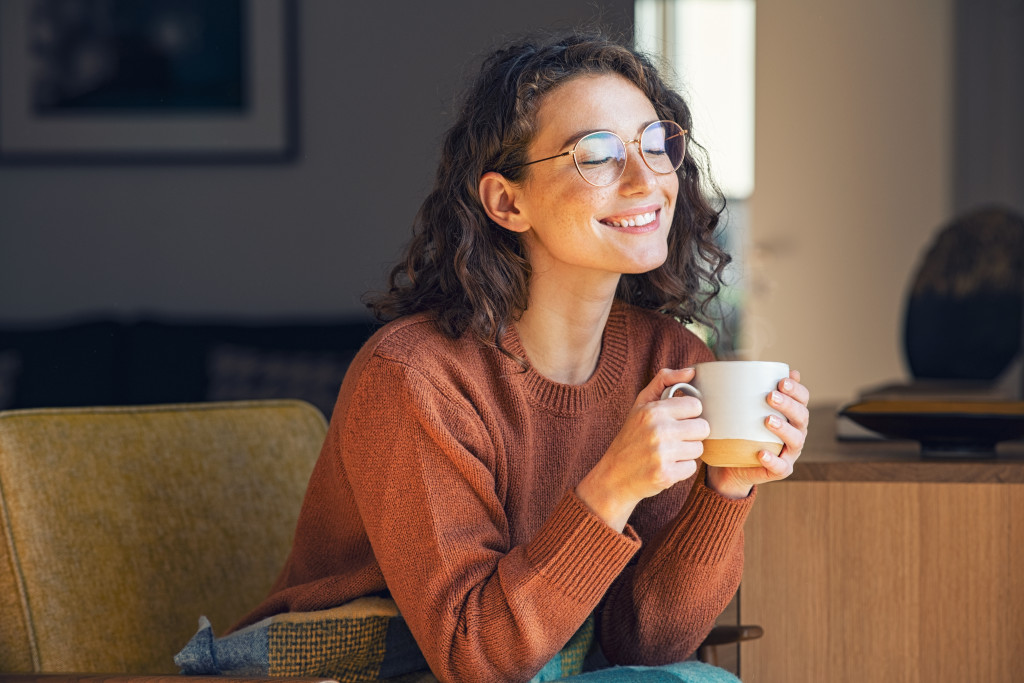 Young woman relaxing on a couch at home while drinking hot chocolate.