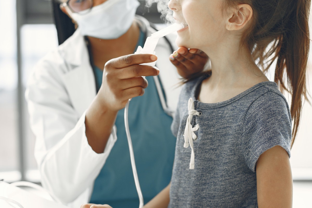 A Doctor Giving Medication to a Girl through a Nebulizer