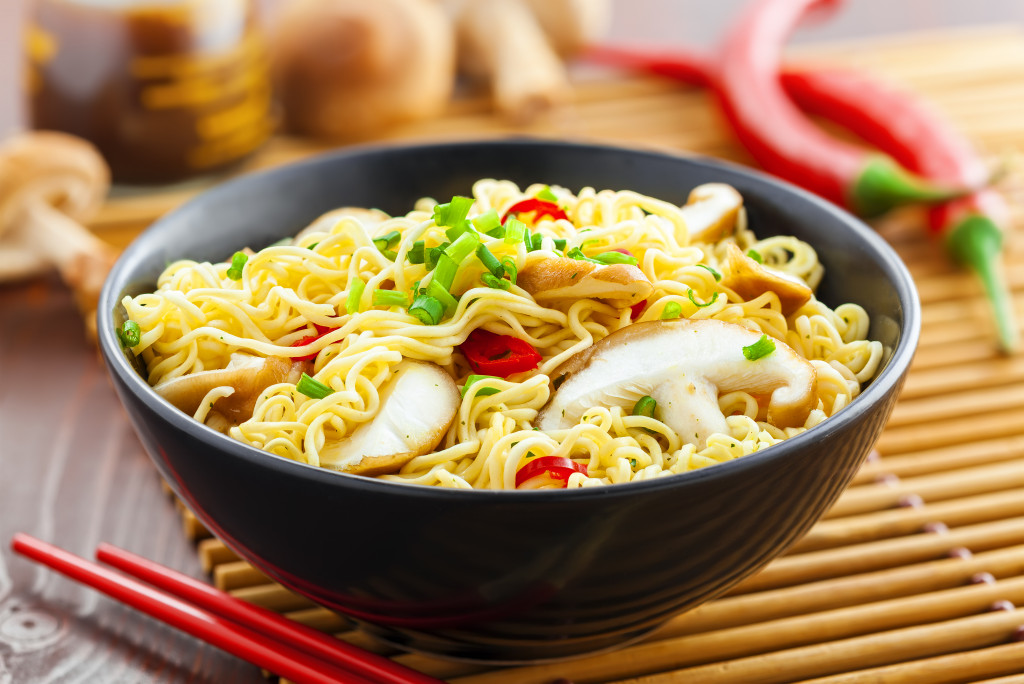 noodles in a black bowl with asian ingredients around