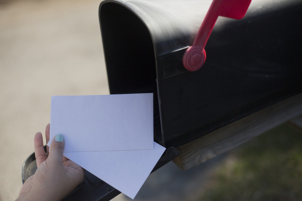 A person putting mail in a mailbox