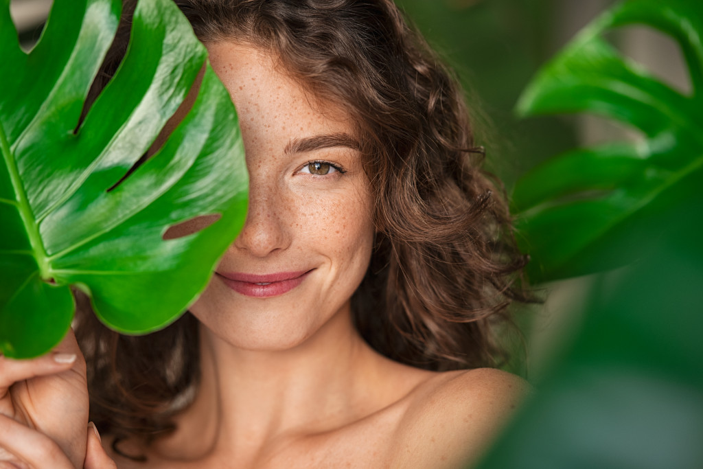 woman smiling behind the leaf