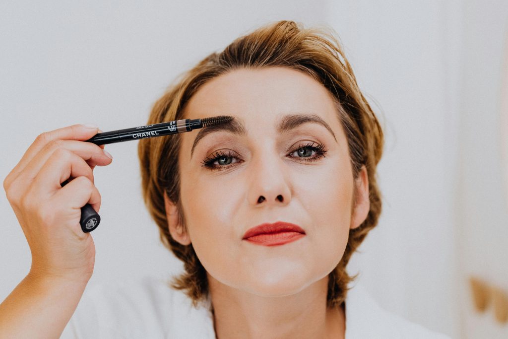 woman filling in her eyebrows using an eyebrow pencil