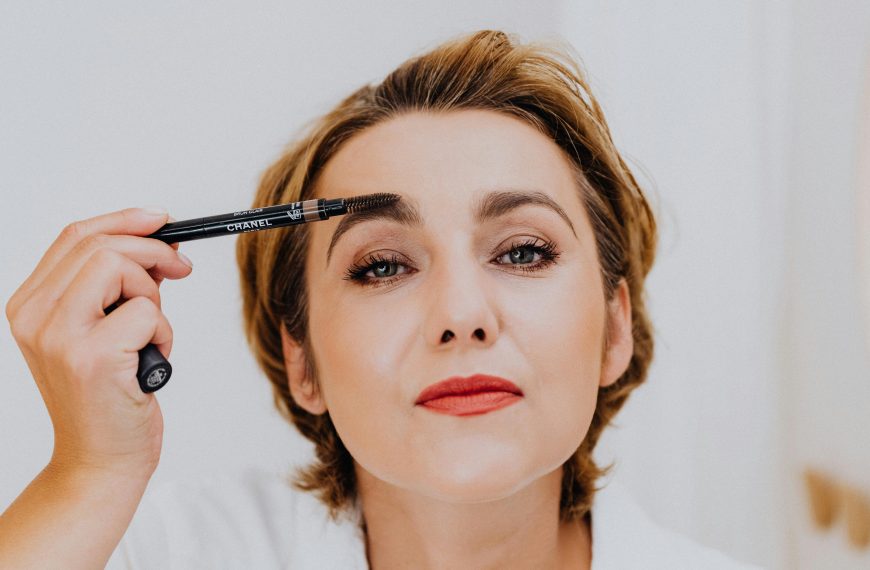 woman filling in her eyebrows using an eyebrow pencil